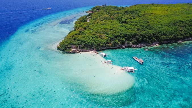 Aerial view of sandy beach with tourists swimming in beautiful c